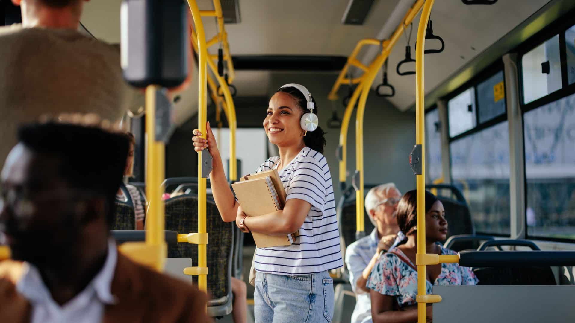 femail Student thats on a bus moving to a new city, wearing headphones and smiling